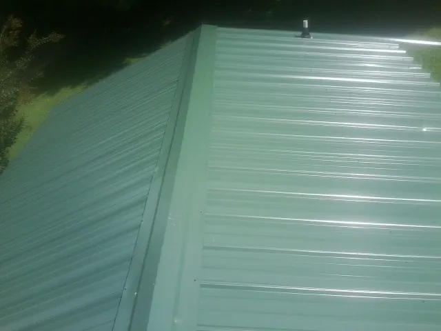 New green metal panels meeting at the ridge of a roof — Flat Roof Repair work by our crew in Lisbon